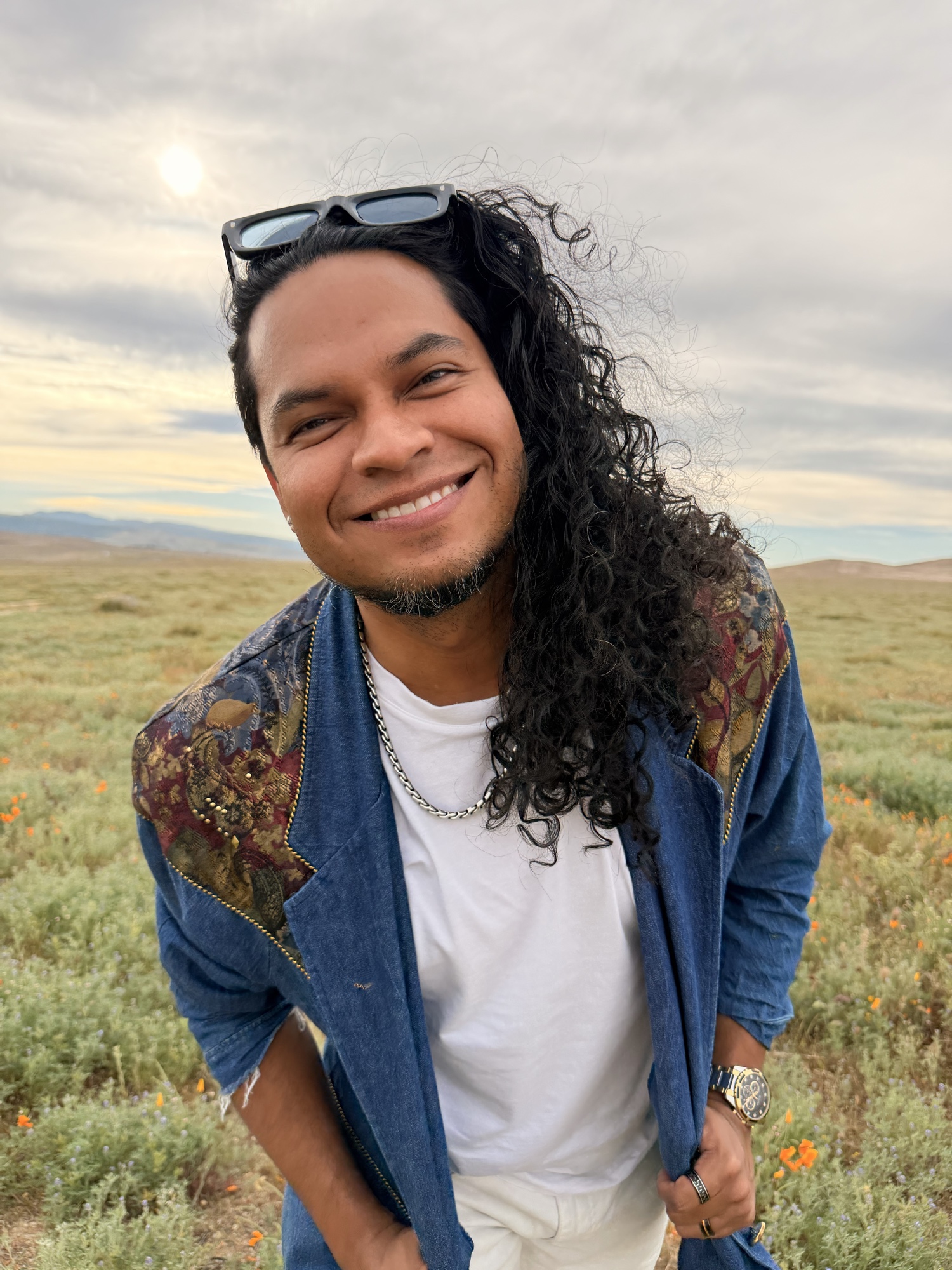 Francisco Ruiz sonriendo al aire libre en un campo de flores silvestres